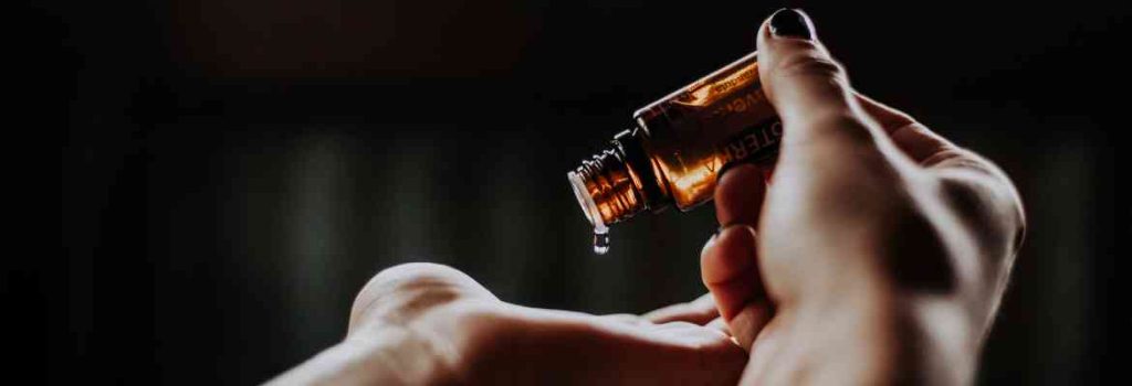 essential oils being dropped into the palm of a hand